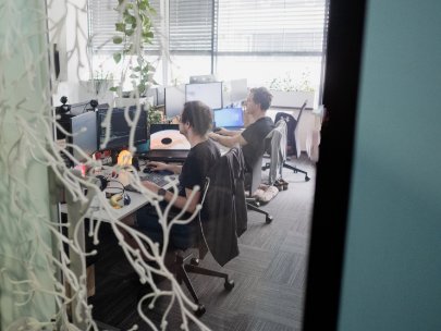 Several people working at desks behind a glass door at Kentico in the Brno office.